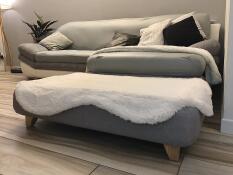 Szare łóżko z białym kożuszkiem i kwadratowymi drewnianymi nóżkami